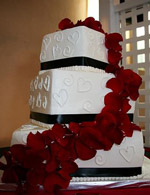 Stacked square wedding cake with hearts and rose petals